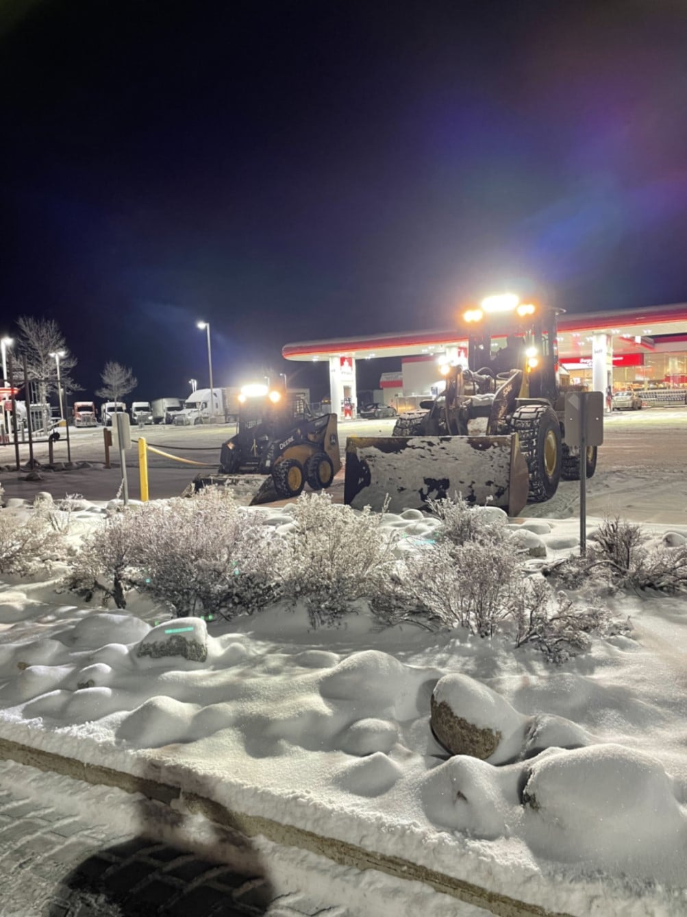 Two snow removal vehicles on the gas station
